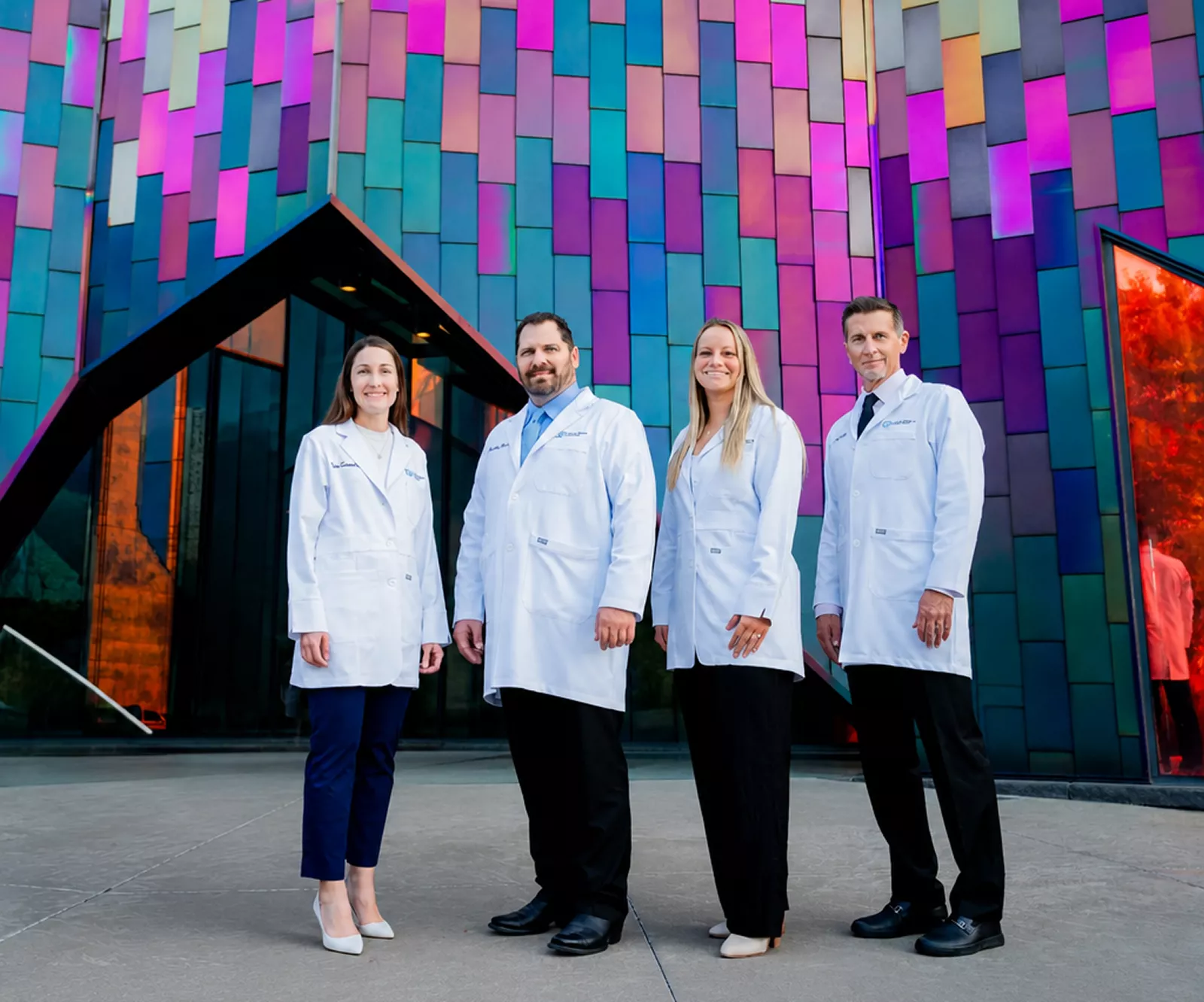 Our surgeons posing outside in front of a colorful wall.